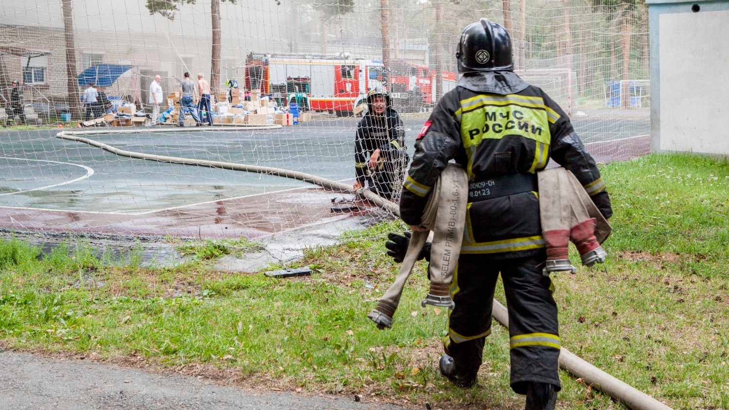 Пожарные протягивают шланг к месту возгорания для подачи воды