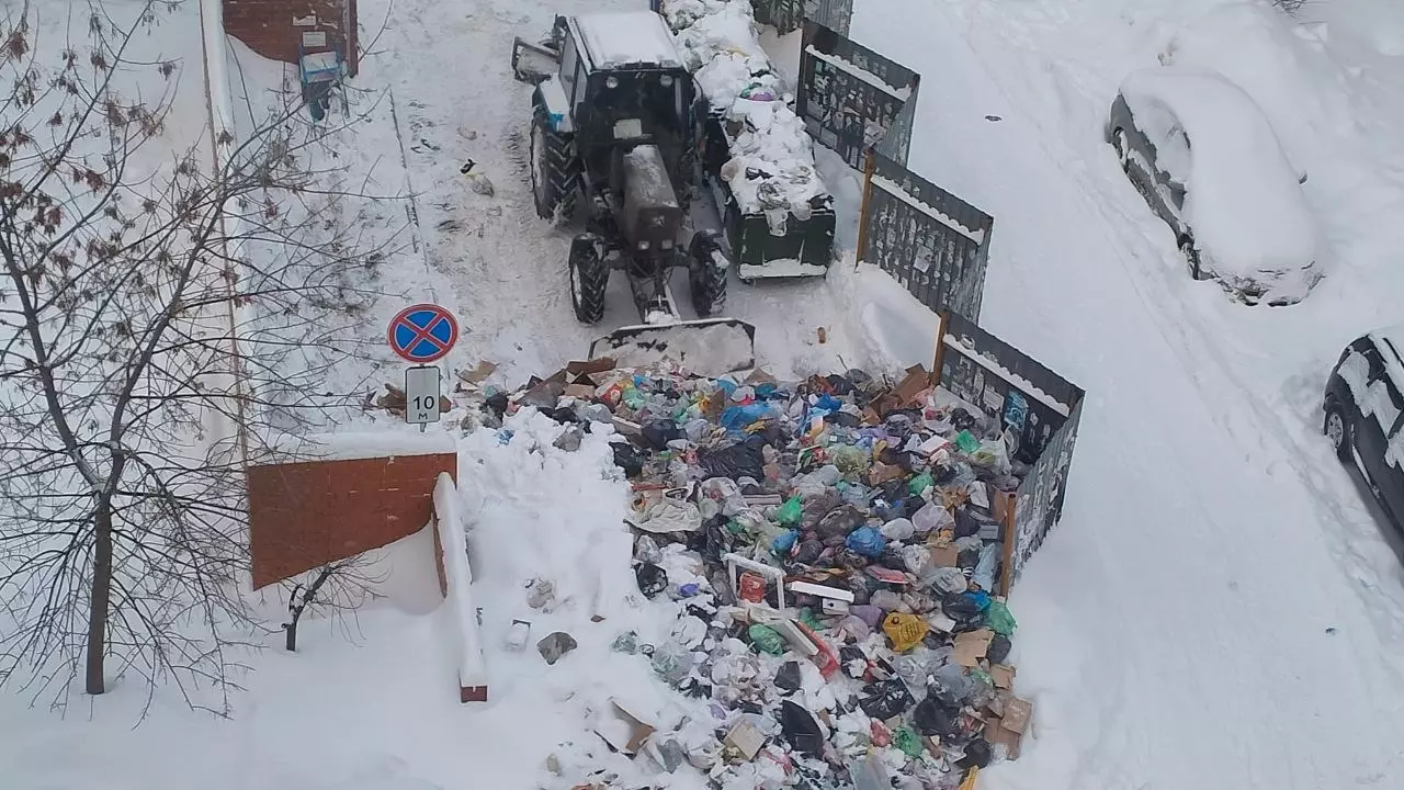 Трактор сдвигает мусорную кучу с контейнерной площадки в Челябинске