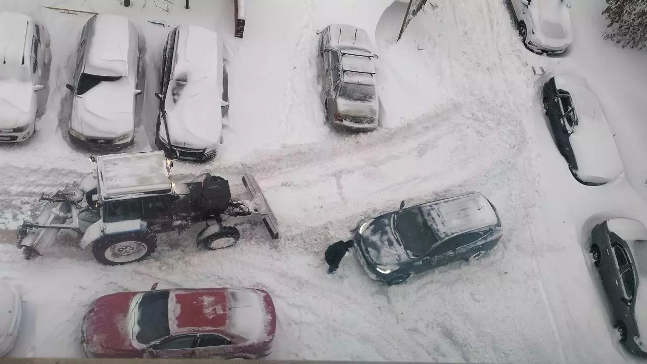 Тракторам чистить снег приходится в условиях узких проездов из-за большого количества припаркованных машин