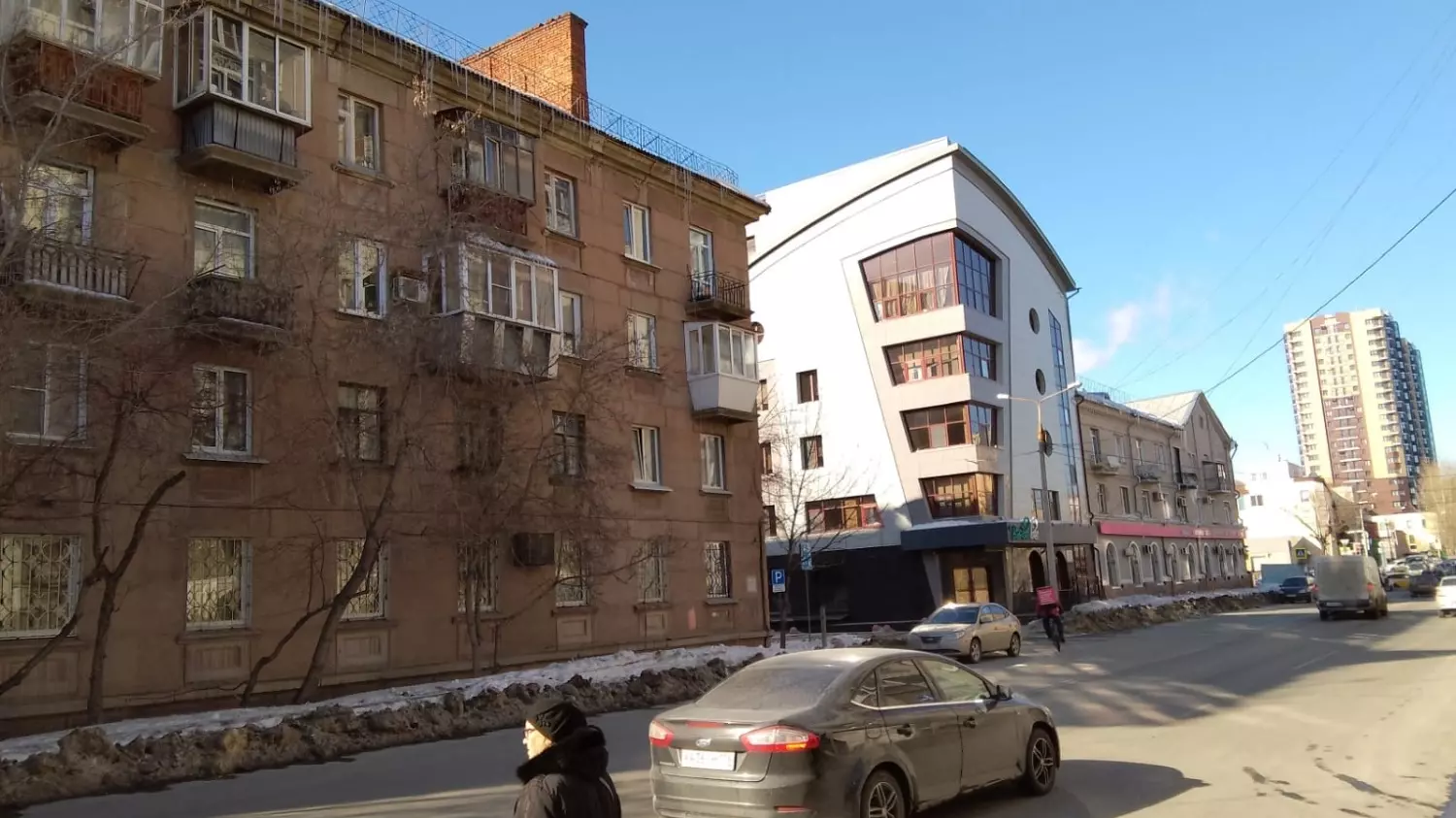 Офисная вставка современной архитектуры странно смотрится рядом с четырехэтажным жилым зданием времен СССР
